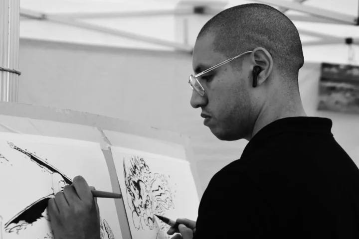 Isia Augustine dessinant simultanément avec ses deux mains lors d’une création artistique à La Réunion.